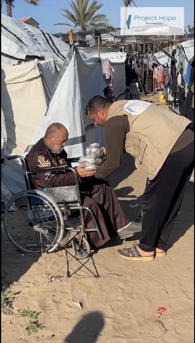 A Project Hope volunteer handing food to an elderly man in a camp