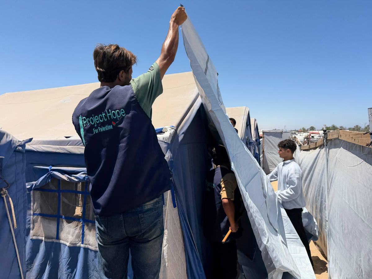 A Project Hope volunteer reinforcing tents in a displacement camp