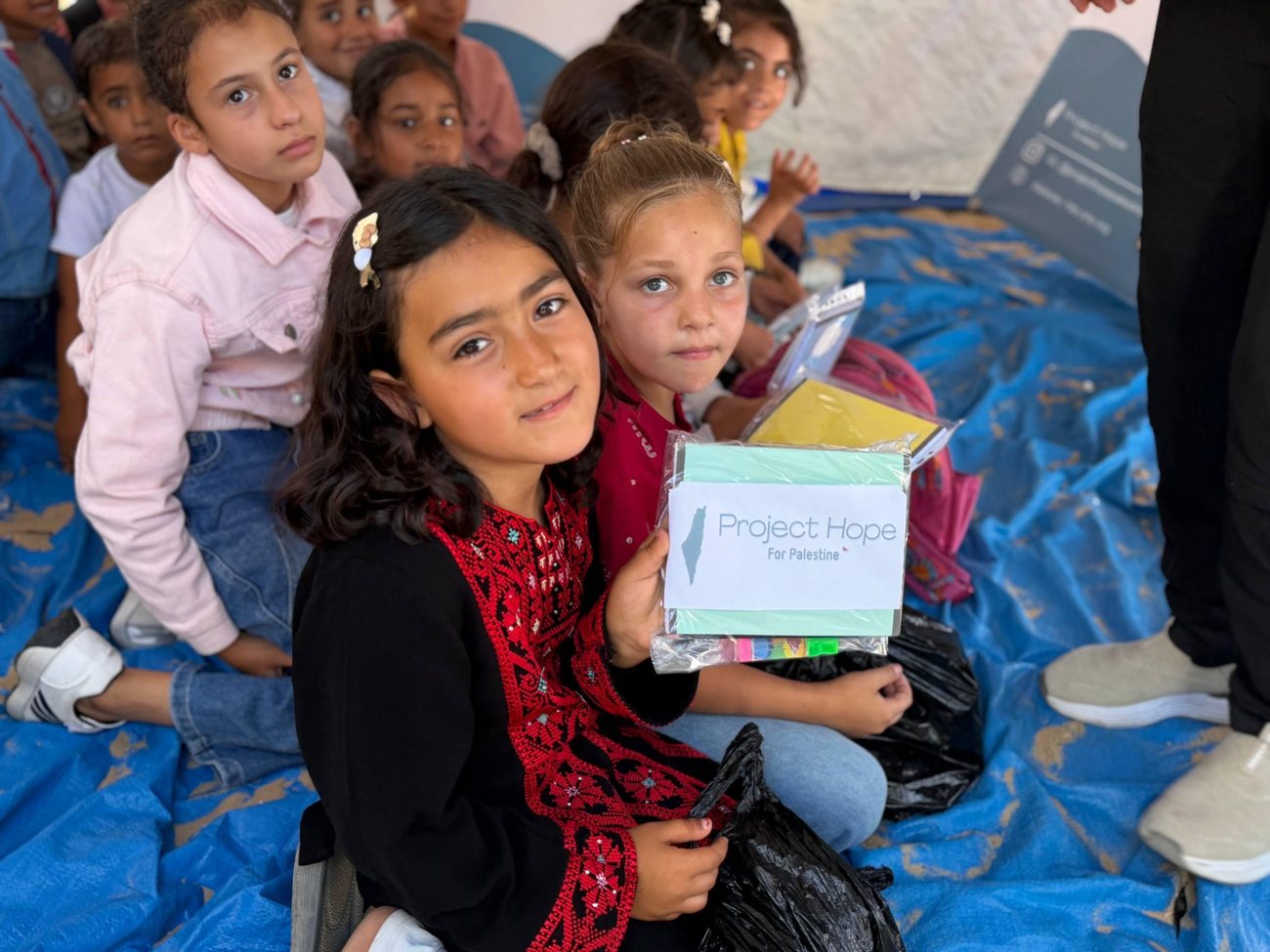 A box of school supplies handed over in a tent classroom.